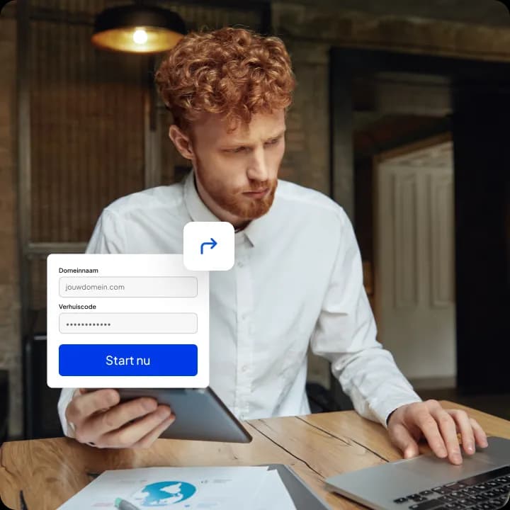 Man met rood krullend haar en baard werkt met een tablet en laptop aan een houten tafel, met in beeld een formulier met de velden 'Domeinnaam' en 'Verhuiscode' en de knop 'Start nu'.